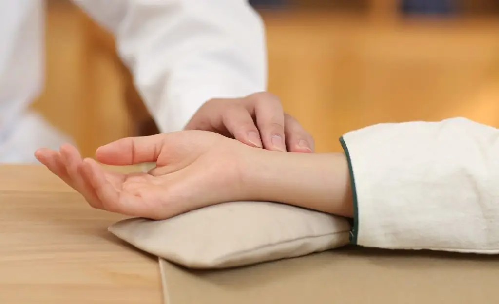 TCM practitioner performing pulse diagnosis on patient at traditional Chinese medicine clinic