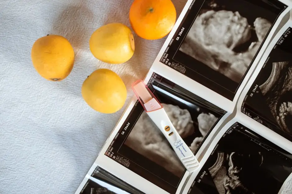 A pregnancy test surrounded by ultrasound scans and lemons on a white surface.